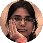 A woman with glasses resting her head on her hand, looking thoughtful.