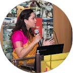 Woman with long dark hair wearing a pink shirt using a smartphone in a store.